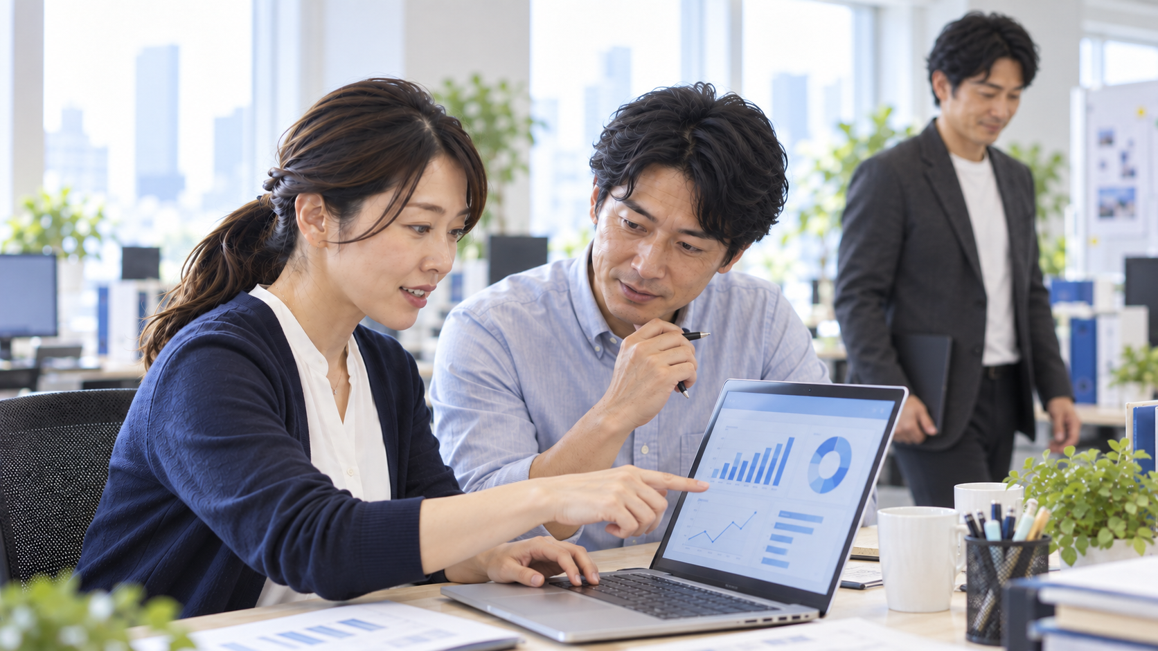 担当者が同僚へ説明し、社内で仕事を続ける様子